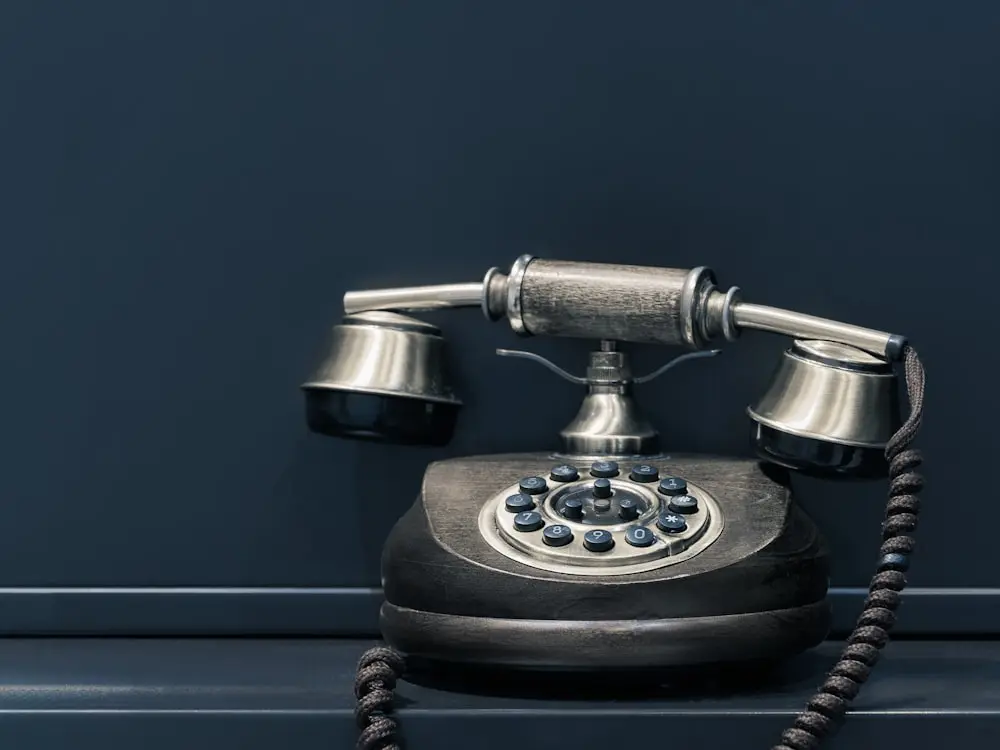 Klassisches Telefon vor tiefblauer Wand — dekoratives Sinnbild für die Akquise, die wir für Sie übernehmen